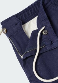 Navy blue pants with button closure, partially open zipper, white drawstring, and visible light beige inner lining at the waistband.