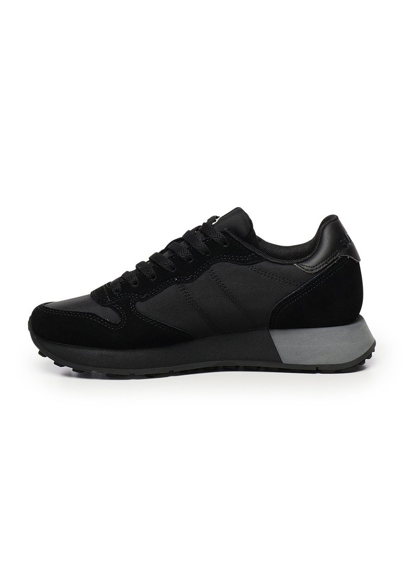 Sneaker bassi neri con pannelli in rete e suede, lacci neri e una spessa suola in gomma grigia e nera, mostrati di lato su sfondo bianco.