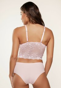Roze kanten cropped top met verstelbare bandjes en een geschulpte zoom, gecombineerd met bijpassende roze high-waisted panties. Glad textuur.