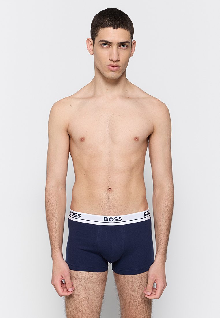 Boxers bleu marine avec une ceinture élastique blanche portant le logo "BOSS". Fabriqués dans un tissu doux et extensible, ils offrent un design ajusté.