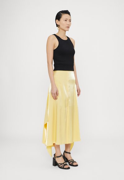 Musthave musta ilma varrukatega top, kollane satiin midi seelik kõrge-krae äärtega ja mustad rihmajalatsid plokknõela ning ümmarguste detailidega.