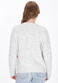 Suéter de punto gris claro con mangas largas, cuello redondo y una textura suave, con un acento rosa en el lado.