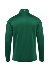 Grön pikétröja med lång ärm och figurnära passform, ribbad krage och subtila sömnadsdetaljer. Tillverkad av mjukt, lätt tyg.