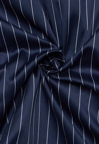 Tessuto blu navy con una superficie liscia, caratterizzato da sottili strisce bianche che corrono verticalmente. Il tessuto è attorcigliato al centro.