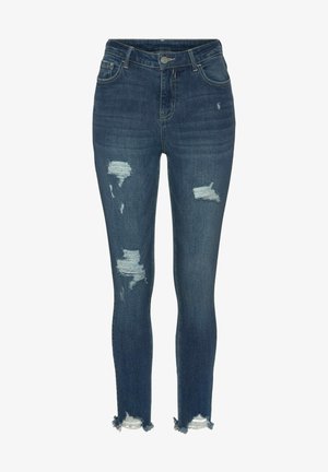 Tievās džinsos tumši zilā denima ar noberzumiem un saplēstiem malām. Iespējo klasisko piecu kabatu dizainu un metāla pogas aizvēršanu.