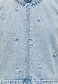 Tissu en denim bleu clair avec de petits détails brodés en forme de papillon. Les lignes de couture visibles et l'encolure ronde rehaussent le design.