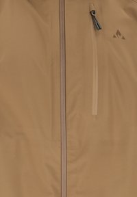 Veste beige avec fermeture éclair à l'avant et poche poitrine zippée verticale dotée de cordons noirs et d'un petit logo triangulaire.