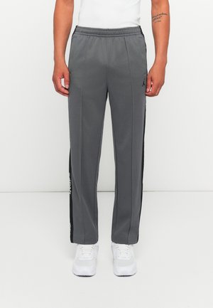 Gray athletic pants with a black side stripe, elastic waistband, and two side pockets. Detailed with a logo on the left hip.