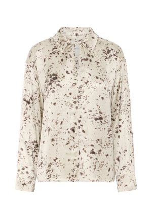 Blusa crema con patrón de manchas marrones; presenta mangas largas, cuello con solapas y una placket de botones parcial. Tejido texturizado visible.