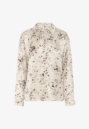 Blusa crema con patrón de manchas marrones; presenta mangas largas, cuello con solapas y una placket de botones parcial. Tejido texturizado visible.