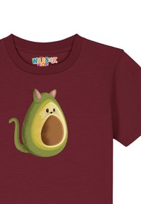 T-shirt en coton bordeaux avec un motif de chat en forme d'avocat, avec un noyau marron et des accents vert clair. Design à manches courtes.