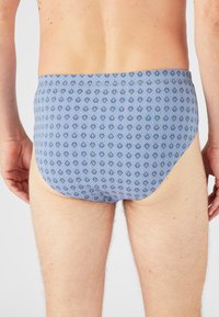 Bañadores azules con un patrón geométrico en azul oscuro y verde. Fabricados con un material suave y elástico, que ofrece un ajuste ceñido con una textura suave.