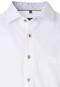 Weißes Button-Up-Hemd mit strukturiertem Kragen. Verfügt über braune Knöpfe und ein blau gemustertes Innenfutter des Kragens. Tasche auf der linken Brust.