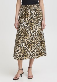 Sukňa midi s leopardím motívom, ktorá má zľahka nariasený elastický pás, jemný materiál a zlaté akcenty. Skombinovaná s čiernymi sandálikmi na vysokom opätku.