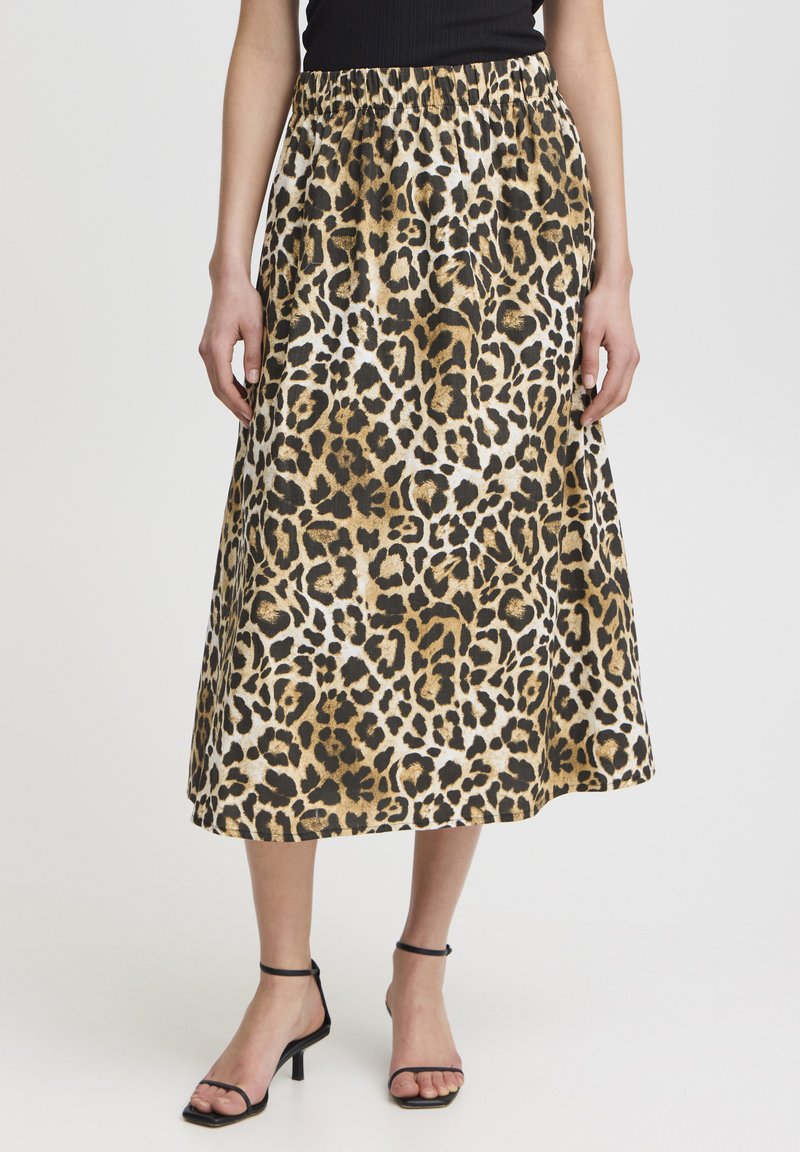 Sukňa midi s leopardím motívom, ktorá má zľahka nariasený elastický pás, jemný materiál a zlaté akcenty. Skombinovaná s čiernymi sandálikmi na vysokom opätku.
