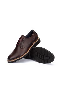 Zapatos de cuero marrón con un acabado suave, cordones en color burdeos que contrastan, suela de goma y costuras detalladas alrededor del borde.