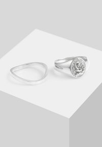 Ensemble de bagues en argent comprenant une bande triangulaire lisse et une bague ornée d'un motif de rose en relief sur une pièce centrale circulaire. Fini brillant.