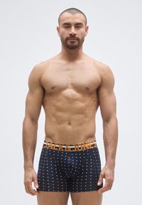 Tummansiniset bokserit oransseilla pilkuilla ja oranssilla vyötärönauhalla, jossa on "JACK & JONES" -logo. Sileä kangas, istuva malli.