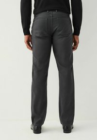 Pilkos kelnes su tiesiomis kelnėmis, turinčios dvi galines kišenes, diržo kilpų ir lygų audinį. Dėvimos su juodais batais.