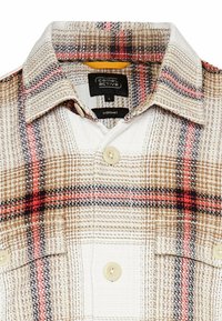 Die Überhemd verfügt über ein kariertes Muster in Beige, Braun und Rot. Hergestellt aus strukturiertem Stoff mit Knopfverschluss und klassischem Kragen.