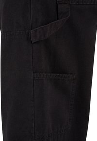 Tissu noir avec une poche cousue et un détail de boucle en tissu au-dessus de la poche sur un vêtement.