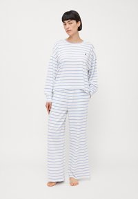Wit pyjamaset met blauwe horizontale strepen, bestaande uit een langmouwtop en losse broek, gemaakt van zachte, lichte stof.