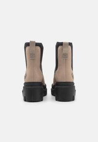 Stivaletti a due toni con tomaia in pelle beige liscia e suola in gomma nera, caratterizzati da una cucitura esterna testurizzata e un'imbragatura per una facile calzata.