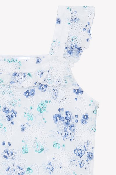 Hvit stoff topp med blå blomsterprint, med volangstropper og blonde detaljer. Glidelås bak. Myk, lett tekstur.