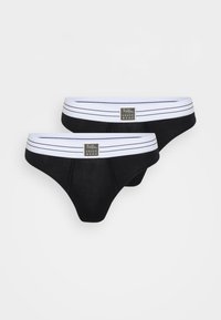 Deux slips noirs en tissu doux, avec une ceinture élastique rayée blanche portant un logo. Texture lisse avec un design ajusté.