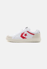 Sneaker alb din piele cu stea roșie și accente chevron, vârf din suede bej și o talpă din cauciuc alb texturat.