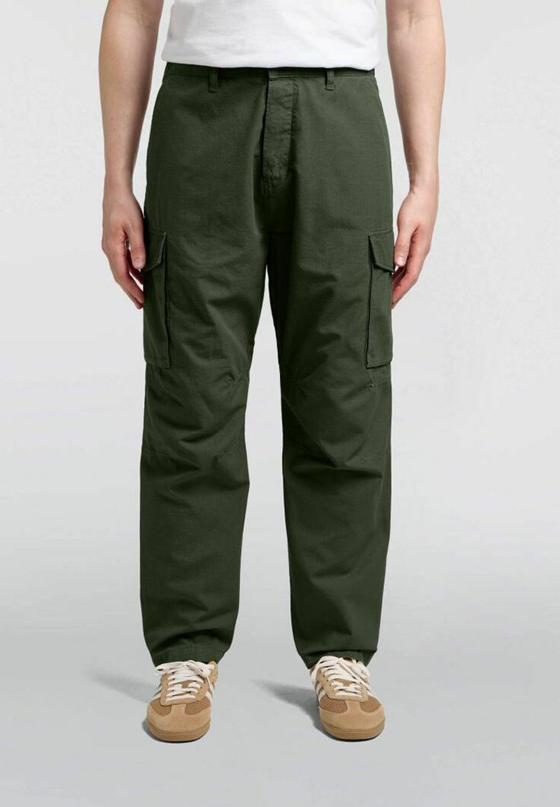 Pantaloni cargo in tessuto verde scuro con una vestibilità rilassata, dotati di due tasche laterali e cuciture rinforzate, abbinati a sneaker beige.