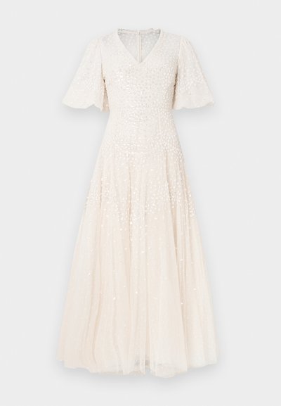Svetlo béžové šaty dĺžky po členky s výstrihom do V, krátkymi zvonovitými rukávmi a zdobené flitrami. Jemná tylová látka pridáva textúrovanú vrstvu.