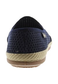 Zapato de malla azul marino tipo slip-on con suela tejida beige y parte inferior de goma, visto desde la parte trasera.