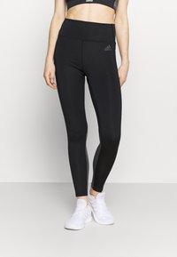 Mustat korkeavyötäröiset legginssit joustavasta materiaalista, joissa on tyylikäs muotoilu ja huomaamaton logodetail. Yhdistetty valkoisiin urheilukengiin.