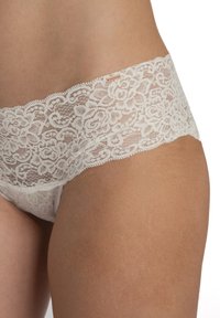 Čipkaste hlačke z širokim cvetnim čipkastim trakom v odtenku off-white, mehke teksture in brezšivnimi robovi, ki poudarjajo nežne cvetlične vzorce.