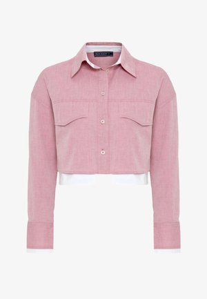 Camisa corta de tejido rosa claro con cierre de botones en la parte delantera, dos bolsillos en el pecho y detalles en blanco en los puños.