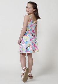 Buntes, ärmelloses Kleid aus einem gemusterten Stoff mit Herzen und dem Wort "Liebe" in Schwarz. Das Kleid weitete sich von der Taille.