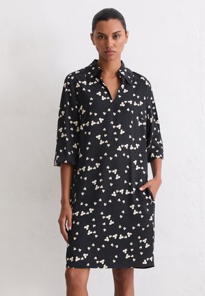 Black dress with a collared neckline, three-quarter sleeves, and a loose fit. Features a white floral pattern and side pockets.