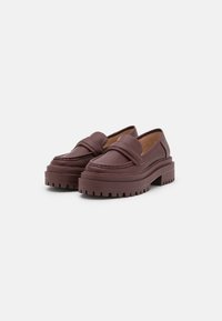 Mocasines de cuero burdeos con suela de plataforma gruesa, costuras decorativas y una cinta ancha en la parte superior. Suela de goma texturizada.