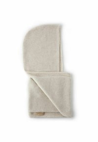Jasnobeżowy dzianinowy koc o miękkiej fakturze, złożony z zaokrąglonym rogiem. Posiada metkę z nazwą marki oraz staranne wykończenie brzegów.