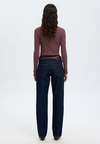 Mørkeblå høytlivsjeans med rette ben og minimal søm. Kombinert med en tettsittende burgunder og hvit stripete langermet topp.