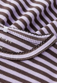 Tissu rayé avec des couleurs alternées de lavande et de marron, présentant une texture côtelée. L'encolure présente un détail de couture contrasté.