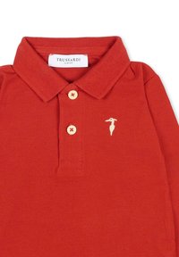 Rode polo met een gestructureerde stof, voorzien van een kraag, drie knopen en een klein geborduurd logo in het wit op de borst.