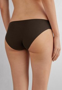 Hnědé bikiny s hladkým a jemným povrchem a nízkým pasem s vysokými výřezy na nohavicích, které vyjadřují minimalistický styl.