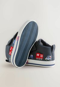 Jūras spēku kanvas apavi ar transportlīdzekļu izšuvumiem, balta gumijas zolīte un āķa un cilpas stiprinājumi. Teksturēta zole nodrošina saķeri un stabilitāti.