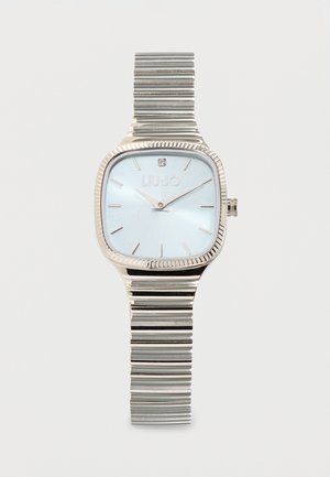 Reloj de pulsera plateado con esfera cuadrada azul, marcas de hora minimalistas y correa metálica extensible que muestra la hora 10:10.