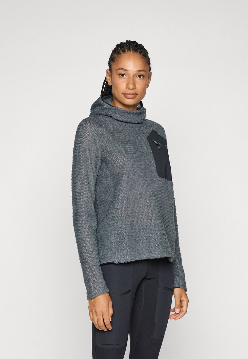 Hoodie gris texturé avec un col drapé, doté d'une poche patch noire sur le côté gauche et d'une coupe décontractée. Porté avec un pantalon noir.