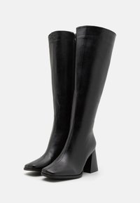 Knee-high black leather boots with a square toe, chunky high heel, and a side zipper; smooth texture with a sleek design.