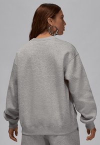 Grå hettegenser med en avslappet passform, ribbede mansjetter og hem. Stoffet ser mykt ut, med en matt tekstur og enkelt design.