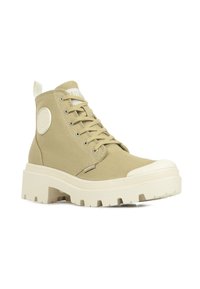 Sneaker high-top beige realizzato in tela, con suola spessa in gomma bianca, occhielli argentati e un'etichetta con logo testurizzato sul lato.